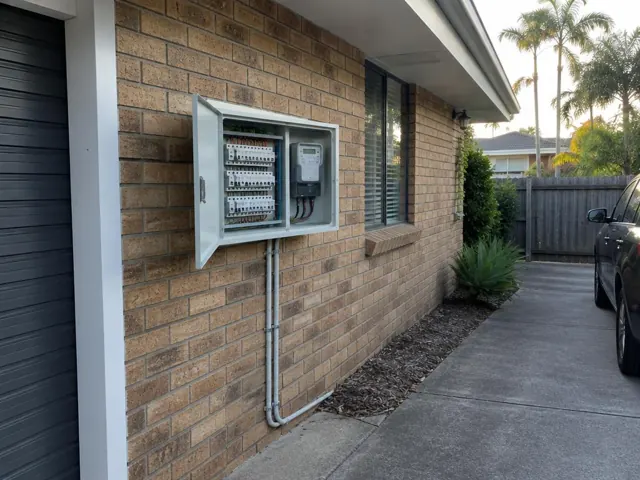 Outdoor switchboard cabinet on a brick house wall beside a driveway in Mermaid Beach
